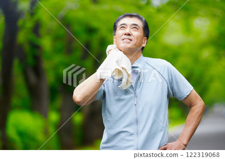 Smiling senior man wiping sweat off in the park 122319068
