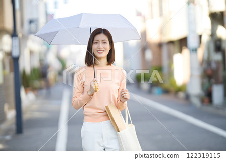 A middle-aged woman walking through the city with a parasol 122319115