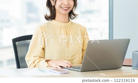 Smiling woman/businesswoman using a computer in the office Smiling woman/businesswoman using a computer in the office 122319119