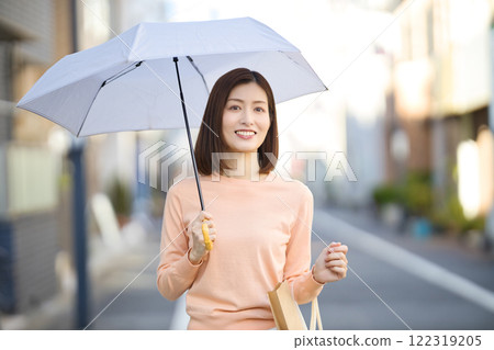 撐著遮陽傘在城裡散步的中年婦女 撐著遮陽傘在城裡散步的中年婦女 122319205