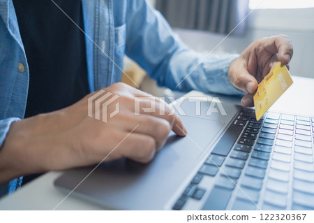Man holding credit card while using laptop, shopping online, buying on internet. e-commerce e-banking service. 122320367