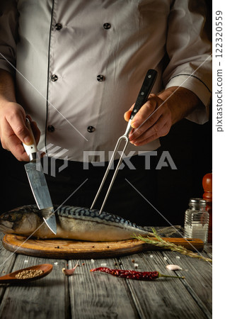 A skilled chef is filleting a fresh fish using a sharp knife while holding it steady with a fork. The chef's focused demeanor highlights the precision of the culinary art in a cozy kitchen A skilled chef is filleting a fresh fish using a sharp knife while holding it steady with a fork. The chef's focused demeanor highlights the precision of the culinary art in a cozy kitchen 122320559