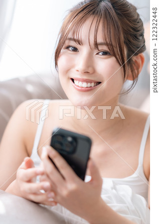 年輕女子在房間裡看著智慧型手機螢幕 年輕女子在房間裡看著智慧型手機螢幕 122322448