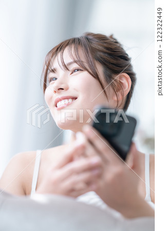 度假時，年輕女子在沙發上查看手機 122322449