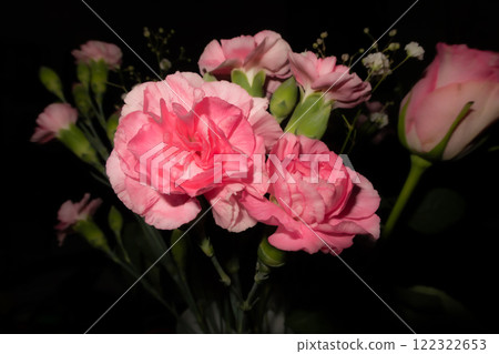 Close-up photo of a bouquet of pink roses showing the texture, pattern and detail. Black background 122322653