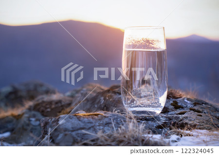 Pure natural drinking soda mineral water in a glass at the top of the mountain in winter. The frosty freshness of thirst A Refreshing Glass of Clear Water Against the Beautiful Backdrop of a Mountain Pure natural drinking soda mineral water in a glass at the top of the mountain in winter. The frosty freshness of thirst A Refreshing Glass of Clear Water Against the Beautiful Backdrop of a Mountain 122324045