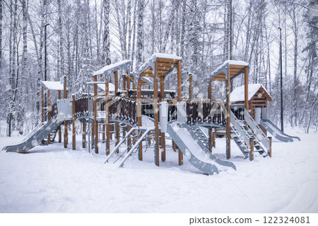 Children's playground is a town for playing in the winter forest. A snowy playground with vibrant slides and climbing structures, nestled in a magical winter wonderland. 122324081