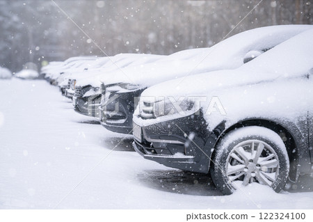 Snowfall, Snow-covered cars in a row in the parking lot. A group of snowcovered cars parked in a winter parking lot during a chilly season Snowfall, Snow-covered cars in a row in the parking lot. A group of snowcovered cars parked in a winter parking lot during a chilly season 122324100