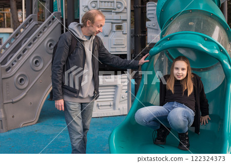 Joyful father with his child girl playing together on playground 122324373