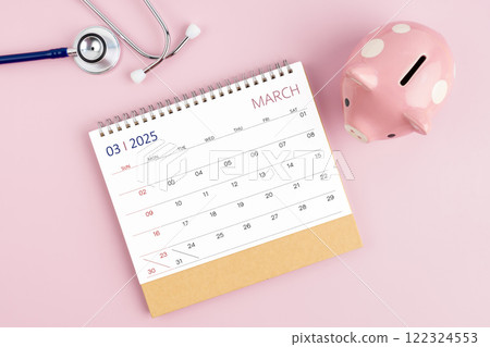 March 2025 desk calendar and stethoscope with piggy bank, Savings for Health insurance. 122324553