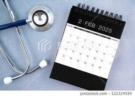 February 2025 desk calendar and stethoscope, Medical appointment schedule to check up. 122324584