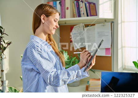 Young female teenager with digital tablet, at home Young female teenager with digital tablet, at home 122325327