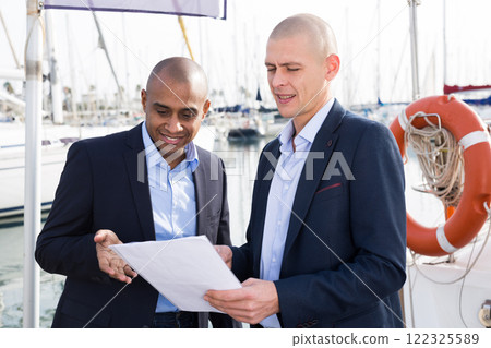 Two men in suits buy and sell a yacht in the seaport 122325589