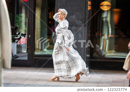 Elegant mature woman wearing long plaid dress and stylish accessories Walking confidently in urban Street near modern building, timeless fashion and sophistication. Fashion Model of Middle Age Elegant mature woman wearing long plaid dress and stylish accessories Walking confidently in urban Street near modern building, timeless fashion and sophistication. Fashion Model of Middle Age 122325774