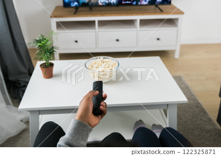 Remote control is pointed toward the television screen, control and choice of tv entertainment. TV, series and streaming service concept Remote control is pointed toward the television screen, control and choice of tv entertainment. TV, series and streaming service concept 122325871