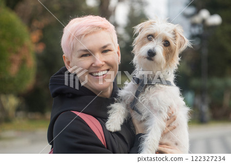 Attractive affectionate mature woman embracing pet dog Jack Russell Terrier in nature 122327234