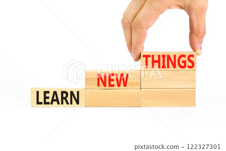 Learn new things symbol. Concept words Learn new things on beautiful wooden blocks. Beautiful white table white background. Businessman hand. Business motivational learn new things concept. Copy space 122327301