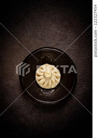 one khinkali, on a black plate, top view, cooking concept, Georgian cuisine, 122327454