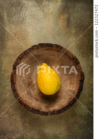 Yellow fruit placed in a rustic wooden bowl on a textured surface, highlighting the simplicity of natural elements in a well-composed arrangement Yellow fruit placed in a rustic wooden bowl on a textured surface, highlighting the simplicity of natural elements in a well-composed arrangement 122327472