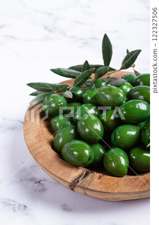 Halkidiki olives, classic Greek green olives, in a wooden bowl, on a marble table, no people, 122327506