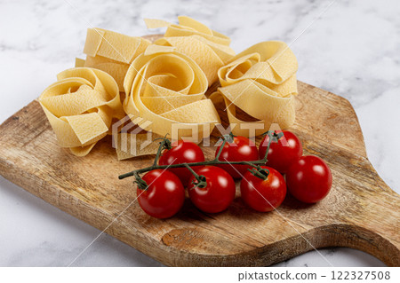 raw pappardelle pasta, on a wooden chopping board, with cherry tomatoes, top view, no people, raw pappardelle pasta, on a wooden chopping board, with cherry tomatoes, top view, no people, 122327508
