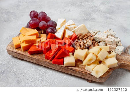 Assorted cheese on a wooden board, with grapes and walnuts, appetizer, no people. 122327520