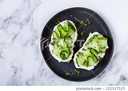 Breakfast, grain bread sandwiches, cream cheese, sliced cucumber, with microgreens, and sesame seeds, on a light table, close-up, top view, selective focus, no people, 122327525