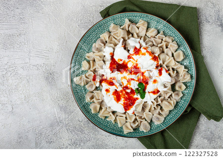 Traditional Turkish dumplings served with yogurt and spicy sauce on a green decorative plate 122327528