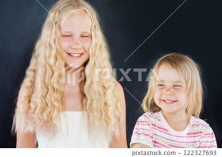 Happy young girls sisters laughing on black background portrait Happy young girls sisters laughing on black background portrait 122327693
