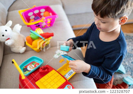 A child plays store with a toy cash register. A child plays store with a toy cash register. 122328707