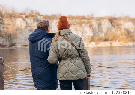 Millennial guy and girl enjoying autumn day out. Lifestyle and tourism concept. Rear view. Couple man and woman walking together holding hands enjoying mountains and lake outback nature 122328812