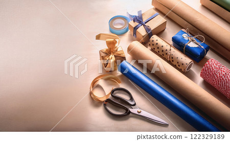 Creative workspace with wrapping materials, including scissors, ribbons, and rolls of paper, perfect for gift wrapping and crafting projects 122329189