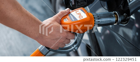Close-up detail view of fuel autogas pump gun connected with noozle adapter to car tank to refill at car gas filling station. Refueling vehicle with liquefied lpg or lng product. Safety technology 122329451