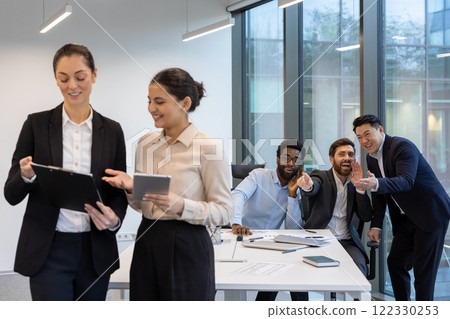 Unethical behavior, harassment. Men mocking female colleagues inside the office. Unethical behavior, harassment. Men mocking female colleagues inside the office. 122330253