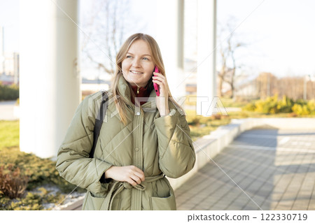 Happy 30s woman talking phone and look happy outdoors. Urban lifestyle concept. Spring time. Beautiful woman walking on the modern city street. 122330719