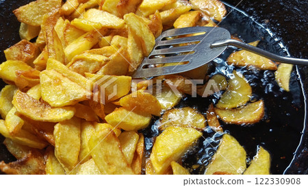 Tasty crispy fried wedges of potato with fresh rosemary served in an old metal skillet in a close up wide 122330908