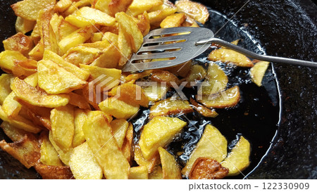 Tasty crispy fried wedges of potato with fresh rosemary served in an old metal skillet in a close up wide 122330909