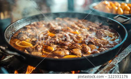 Juicy meat sizzling in a large pan outdoors 122331176
