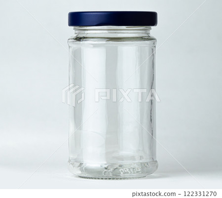 A transparent glass jar stands empty against a neutral background A transparent glass jar stands empty against a neutral background 122331270