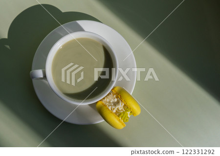 Green latte matcha with yellow macaron dessert on pastel background with creative deep shadows. Concept of holiday breakfast morning tea drink. Cozy minimalist superfood vibrant colors healthy eating Green latte matcha with yellow macaron dessert on pastel background with creative deep shadows. Concept of holiday breakfast morning tea drink. Cozy minimalist superfood vibrant colors healthy eating 122331292