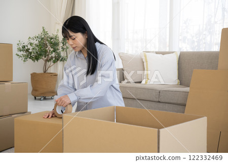 A woman putting duct tape on cardboard 122332469