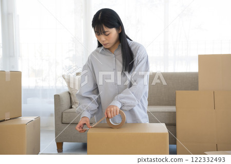 一名婦女將膠帶貼在紙板上 一名婦女將膠帶貼在紙板上 122332493