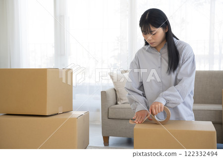 A woman putting duct tape on cardboard A woman putting duct tape on cardboard 122332494