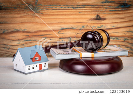 Inheritance dispute. Judge's gavel, money and miniature house on a wooden texture backgroun Inheritance dispute. Judge's gavel, money and miniature house on a wooden texture backgroun 122333619