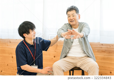 Senior man doing exercises for rehabilitation and male staff including physical therapist and occupational therapist 122334843