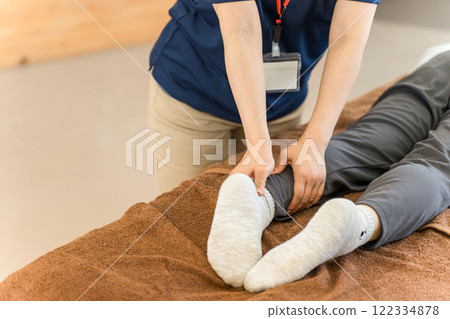 A female massage therapist and physical therapist massaging a senior woman 122334878