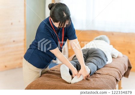 A female massage therapist and physical therapist massaging a senior woman 122334879