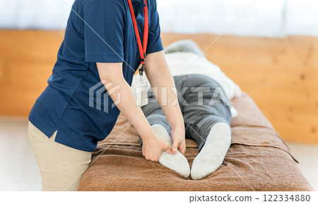 A female massage therapist and physical therapist massaging a senior woman A female massage therapist and physical therapist massaging a senior woman 122334880