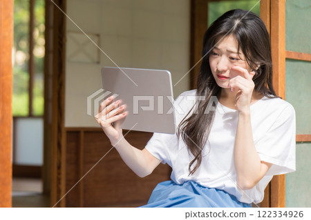 A young woman is moved by watching a video on a tablet A young woman is moved by watching a video on a tablet 122334926