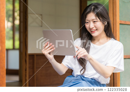 A young woman looking at a tablet and touching it A young woman looking at a tablet and touching it 122335028